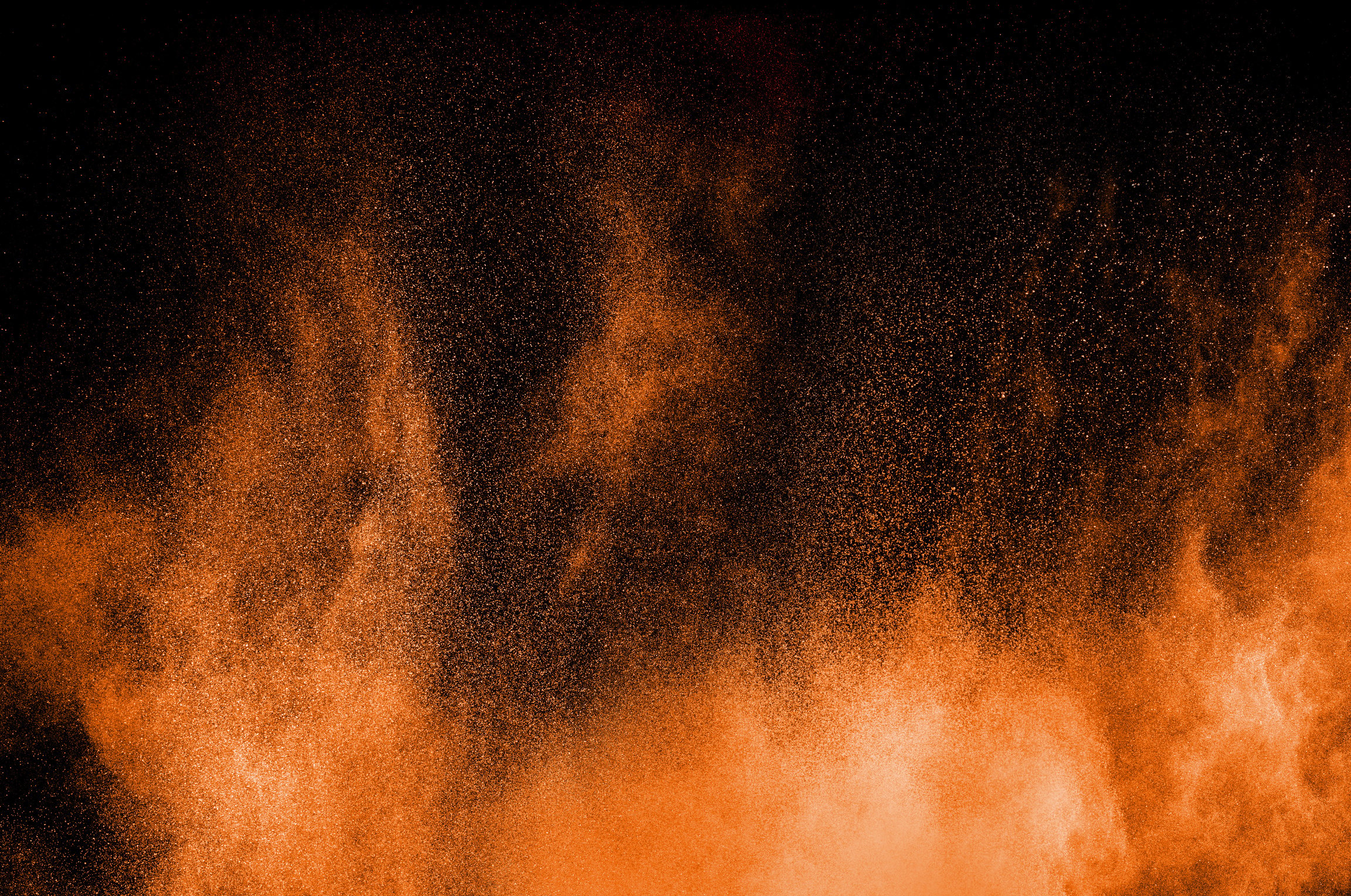 Orange powder explosion on black background. Orange color dust splash.